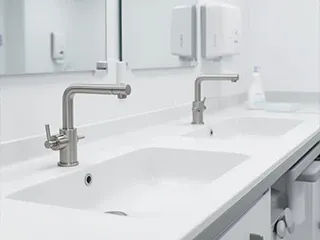 Bancada branca com duas torneiras e dispensers